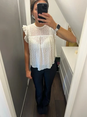 Vit spetsblus med volangärmar från Nelly - Söt vit blus i spets med volangdetaljer vid ärmarna och transparent tyg. 
