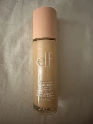 e.l.f. Halo Glow Liquid Filter foundation - Foundation från e.l.f. i nyansen Halo Glow Liquid Filter. Kommer i en glasflaska med ljusrosa lock och har en ljus beige ton. Ger glowig finish och kan användas både som bas eller highlighter. Perfekt för dig som vill ha naturlig lyster.