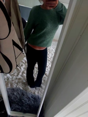 Grön stickad tröja med rund hals - Mysig grön stickad tröja med avslappnad passform och rund halsringning. Tröjan har långa ärmar och är något croppad i modellen, vilket ger en trendig look. Perfekt att matcha med jeans eller kjol för en chill outfit. Den är i ett bra skick för att ha används mycket under en period, kan va lite nopprig men inget man tänker på!