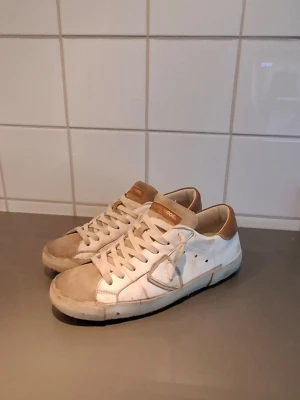 Philippe model - Snygga philippe model skor med beige och bruna detaljer. Skorna har vita snören, beige tåparti och brunt parti vid hälen samt på plösen. Klassisk låg modell med perforerade sidor och gummisula. Storlek 39! Köp!!