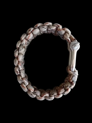 Flätat paracordarmband  - Säljer ett snyggt armband i beige och bruna toner, flätat av slitstarkt paracord. Armbandet har ett robust metallspänne som ger en cool och industriell känsla. Perfekt accessoar för dig som gillar outdoor eller streetwear. Överlevnadsarmband. Paracordarmbandet kan vecklas ut och användas som rep vid behov, exempelvis för att bygga skydd eller fästa utrustning.