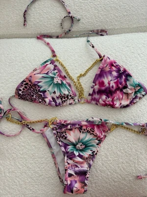 Blommig bikini med guldkedjor - ✨Rosa bikini med blommigt mönster och guldfärgade kedjedetaljer. Justerbar passform och väldigt fin på. Använd få gånger och i mycket fint skick.