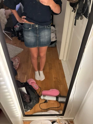 Blå jeanskjol med fickor - Säljer en klassisk blå jeanskjol i kort modell med fram- och bakfickor samt knapp- och dragkedjestängning. Kjolen har en lätt tvättad look och passar perfekt till en avslappnad stil. Snygg att matcha med sneakers eller boots.
