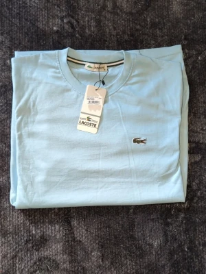 Två stilrena t-shirts från Lacoste & Boss - Säljer två snygga t-shirts: en ljusblå från Lacoste med klassisk krokodillogga och en vit från Boss med diskret logga på bröstet. Båda har rund hals och korta ärmar, perfekta för en clean och fräsch look. Tillverkade i mjuk bomull. Helt nya st Lacoste medium boss xxl (xl) 