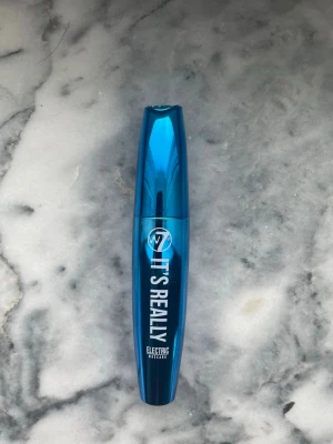 Blå mascara W7 It's Real Electric - Snygg blå mascara från W7 med namnet It's Real Electric. Kommer i en metallicblå tub med matchande borste. Perfekt för dig som vill ha en färgstark look och sticka ut med dina fransar. Enkel att applicera med klassisk spiralborste. Använd en gång 