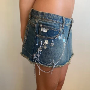 Snygg lågmidjad minikjol 2000s Y2K Vibes  - Lågmidjad jeans minikjol 2000s med kedjor paljetter  pärlemo i sidan . kjolen är ny så fint skick💕