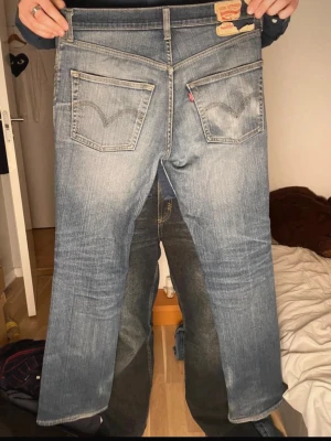 Levi's ljusblå 511 jeans - Säljer ett par ljusblå Levi's jeans 511 med slim passform och slitna detaljer. Jeansen har klassiska bakfickor med V-söm och en liten röd Levi's-tag. Materialet är denim i bomull och de har en snygg tvättad look. 32/32