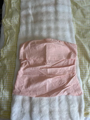 Ljusrosa axelbandslös tubtopp - Säljer en ljusrosa axelbandslös tubtopp med dragkedja i ryggen. Toppen har en enkel och clean design, perfekt för att styla med jeans eller kjol. Materialet känns lätt och passar bra till varmare dagar.