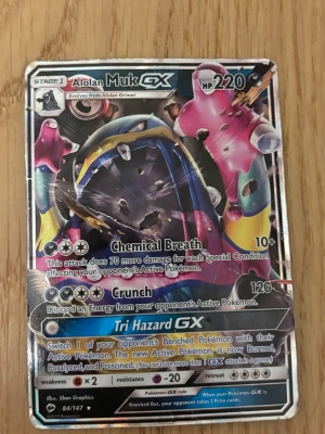 Pokémonkort Alolan Muk GX - Säljer ett Pokémonkort av typen Alolan Muk GX med 220 HP. Kortet har en färgstark och glansig design med attacker som Chemical Breath, Crunch och Tri Hazard GX. Perfekt för samlare eller dig som vill förstärka din lek med en kraftfull GX. Väldig ”rare”