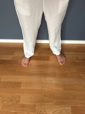Vita linnebyxor med resårmidja - Säljer ett par vita linnebyxor med avslappnad passform och resår i midjan. Byxorna har raka ben och en bakficka. Perfekta för en chill och luftig stil under varma dagar. Materialet är tunt och svalt linne. Modellen är 170 cm väger 54 kg