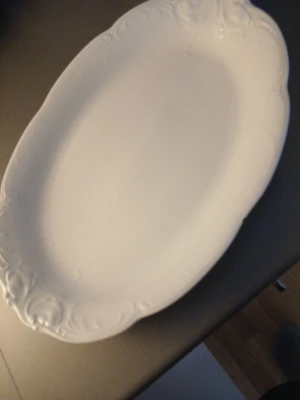 Vit oval serveringsfat porslin - Säljer ett klassiskt vitt ovalt serveringsfat i porslin med dekorativa detaljer längs kanten. Perfekt för att servera mat på middagsbordet eller till festligare tillfällen. Fatet har en elegant och tidlös design som passar de flesta dukningar.