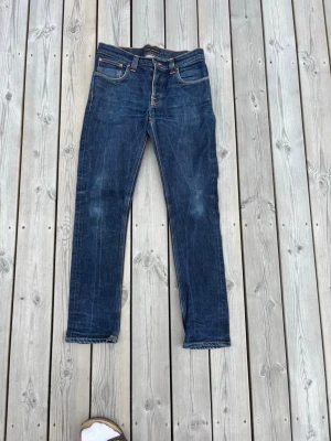 Nudie jeans grim tim - Säljer dessa snygga nudie jeansen i modellen ”grim Tim”, storlek W33, L32. De är lite små i storleken, skulle säga att de passar W31. (Angå gärna efter mått).         De är i riktigt fint skick, inga defekter!          Hör gärna av dig vid funderingar😁