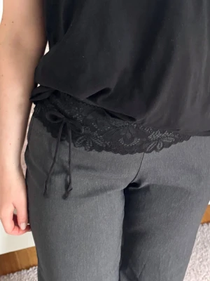 Svart spetsbälte med rosett  - Snyggt svart bälte i spets med dekorativt mönster och rosett i sidan. Perfekt för att ge outfiten en extra detalj och markerad midja. Bältet och flexibelt, passar till både byxor och kjol🌟🌟🌷