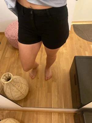Jeans shorts  - Snygga svarta shorts med klassisk femficksdesign och knapp- samt dragkedjestängning. Modellen är midwaist/ highwaist. Från Gina tricot 