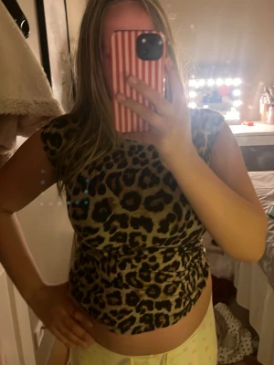 Leopardmönstrad topp med cap sleeve - Snygg leopardmönstrad topp med cap sleeve och figurnära passform. Toppens mönster går i beige och bruna toner med svarta detaljer. Perfekt för dig som vill sticka ut med en trendig look.