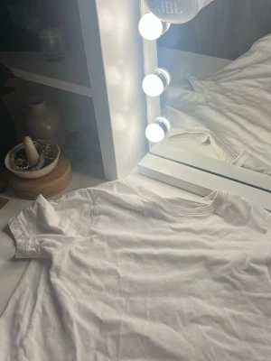 Vit t-shirt från Lindex - En klassisk vit t-shirt från Lindex i mjuk bomull. T-shirten har rund halsringning och korta ärmar, perfekt för en enkel och clean look. Passar till det mesta och är lätt att styla med andra plagg. Org pris 129 så du sparar 30 kr💓💓😽😽