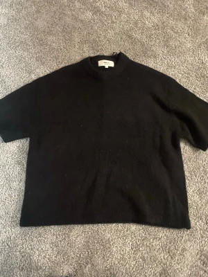 Svart stickad tröja Gina Tricot - Svart stickad T-shirt från Gina Tricot. Aldrig använt endast blivit liggandes. Storlek S men skulle nog även kunnat passa M💕
