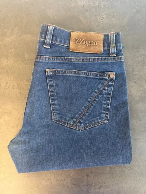 Blå raka jeans från Z Zegna, stl 32 - Snygga blå jeans från Z Zegna med klassisk rak passform och femficksdesign. Jeansen har en stilren look med normalhög midja och är tillverkade i denim. Perfekta för dig som gillar en tidlös och clean stil.