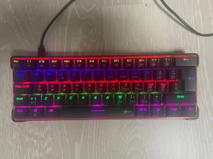 RGB-belyst kompakt gamingtangentbord kopplingsbar ps5/xbox - Säljer ett kompakt mekaniskt tangentbord med RGB-belysning i flera färger. Tangentbordet har svart bas och genomskinliga tangenter som släpper igenom ljuset. Har även en sladd som kan kopplas till ps5/ Xbox. Perfekt för gaming eller skrivbordssetup där du vill ha färg och stil.