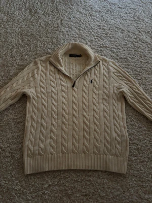 Vit stickad tröja med halvzip från Polo Ralph Lauren - Half-Zip stickad tröja från Polo Ralph Lauren. Använd 2-3 gånger bara. Så nästan som ny. Snygg och skön lite tjockare tröja man kan ha över skjortor, T-shirts osv. 