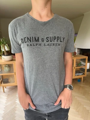 Denim & Supply T-shirt grå vintage herr - Grå Denim & Supply Ralph Lauren t-shirt i mjukt och skönt material. Snyggt, klassiskt vintagetryck på bröstet. Perfekt basplagg till garderoben som passar till det mesta. Mycket fint skick och bra passform. #ralphlauren #denimandsupply #vintagestyle #greytee #herrmode #tshirt #secondhand #vinted #streetwear #classic
