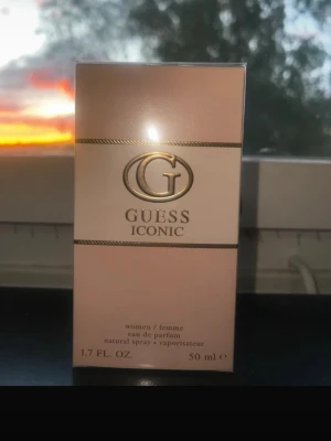 Guess Iconic Eau de Parfum 50 ml - Guess Iconic Eau de Parfum för kvinnor i en elegant ljusrosa och guld kartong. Flaskan rymmer 50 ml och har en lyxig design med Guess-loggan i guld. Perfekt för dig som gillar exklusiva och feminina dofter.