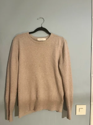 Beige cashmere tröja från Sayless - Mysig beige stickad tröja från Sayless i mjuk cashmere. Tröjan har rund halsringning, långa ärmar och ribbade muddar vid ärmslut och nederkant. Perfekt för dig som gillar stilrena och bekväma plagg. 