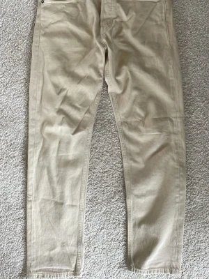 Beige jeans från Jack & Jones - Snygga beige jeans från Jack & Jones i modellen Relaxed-Chris. Byxorna har avslappnad passform, klassiska fickor fram och bak samt knappgylf. Tillverkade i mjukt bomullstyg som ger en skön känsla hela dagen.