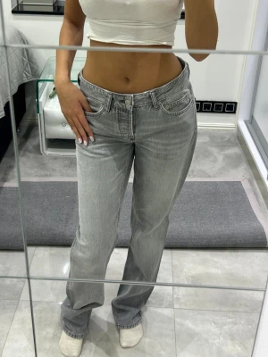 Grå raka jeans med hög midja - Säljer ett par snygga grå jeans med raka ben och hög midja. Jeansen har klassisk femficksmodell och stängs med knapp och dragkedja. Perfekta till en trendig vardagslook och passar till det mesta. Materialet är denim i bomull.