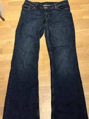Mörkblå bootcut jeans - Snygga mörkblå bootcut jeans med klassisk femficksdesign och orangea sömmar. Jeansen har låg midja och är tillverkade i denim med lätt stretch för skön passform. Perfekt till vardags och till fest. Är i storlek 26/30 men passar S-M och jag är 158cm