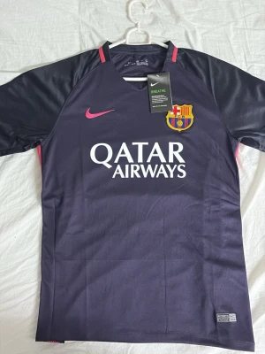 Barça Nike matchtröja lila/rosa - Snygg FC Barcelona matchtröja från Nike i mörklila med rosa detaljer och klubbmärke på bröstet. Qatar Airways-logga framtill och Unicef-tryck bak. Tillverkad i lätt och ventilerande funktionsmaterial, perfekt för fotbollsträning eller match.