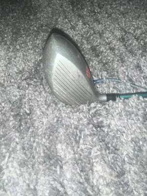 MacGo Hurricane Jumbo golfklubba - MacGo Hurricane Jumbo golfklubba med 11° loft och 250cc klubbhuvud. Klubbhuvudet är i metall med tydliga linjer på träffytan och text i grönt och rött. Perfekt för dig som vill ha en klassisk driver till golfbanan.