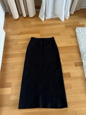 Svart långkjol från Stajl - Klassisk svart långkjol från Stajl med rak passform. Kjolen är enkel och stilren, perfekt att matcha med olika toppar. Tillverkad i ett mjukt material som känns bekvämt mot huden.