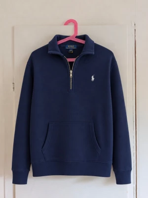 Ralph Lauren 1/4 zip - Polo Ralph Lauren half zip sweatshirt i klassisk marinblå färg med vit broderad Polo-logga 🤍💙 Storlek: M (10–12 år) • Half zip / quarter zip med krage • Broderad vit Polo-logga på bröstet • Stor ficka framtill • Mjuk och varm insida • Ribbad mudd vid ärmar och nederkant • Tidlös och lättmatchad modell Mycket fint begagnat skick utan defekter!😁 En riktigt snygg Ralph Lauren-klassiker som passar perfekt till vardags ✨