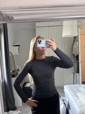 Mörkgrå långärmad topp - En enkel och stilren mörkgrå långärmad topp med rund hals. Toppen har en tight passform och är perfekt att matcha med både jeans och kjol. Materialet känns mjukt och stretchigt, vilket gör den bekväm att bära hela dagen.