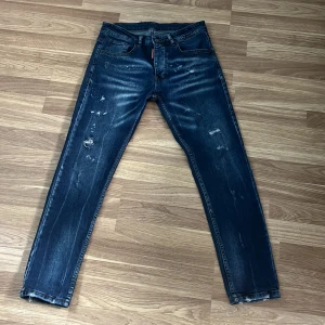 Dsquared2 blå skinny jeans herr - Snygga blå jeans från Dsquared2 med slitna detaljer och skinny passform. Jeansen har klassisk femficksdesign, låg midja och tydliga slitningar framtill för en cool, trendig look. Tillverkade i stretchig denim för extra komfort.