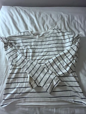 Randig långärmad topp från Lindex - Vit långärmad topp från Lindex med svarta ränder. Klassisk rund halsringning och relaxed fit. Tillverkad i mjuk bomull, långärmad topp med volang💞