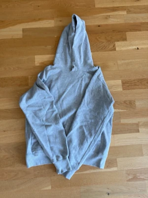 Ljusgrå hoodie med huva från uniqlo - En enkel och stilren ljusgrå hoodie med huva och långa ärmar. Hoodien har en klassisk passform och är tillverkad i mjukt material, perfekt för en avslappnad look. Fickor på sidorna för extra funktionalitet.
