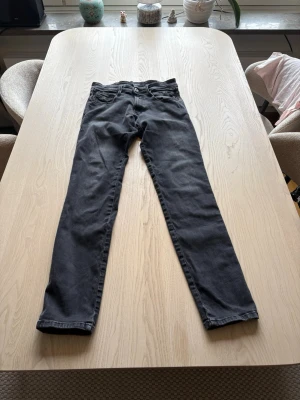 Svarta Replay hyperflex - Snygga svarta replay jeans med klassisk femficksdesign och knappgylf. Jeansen har en smal passform och raka ben, perfekta till en avslappnad stil. Materialet ser ut att vara bomull med lite stretch för extra komfort.