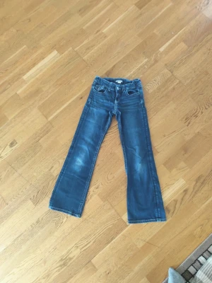 Blå bootcut jeans - Säljer ett par blå bootcut jeans med snygga slitningar på låren och klassiska fem fickor. Jeansen har normal midja och vita kontrastsömmar. Perfekta för en avslappnad och trendig look. Och jag har haft den i 1 år den kostade 350 och jag tycker att den är värd 150, jag säljer den för att den inte passar mig💘