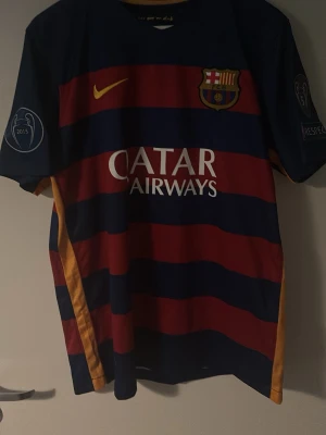 Barcelona Messi matchtröja - Säljer en FC Barcelona matchtröja med Messi och nummer 10 på ryggen. Tröjan har breda blå och röda ränder, gula detaljer och tryck från Qatar Airways och Unicef. Korta ärmar och klubbmärke på bröstet. Perfekt för fotbollsfans!