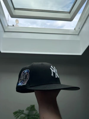 Svart New York Yankees keps - Snygg svart keps från New Era med klassiskt New York Yankees broderat vitt logotyp framtill och en patch på sidan. Säljer för att den var för liten för mig. Köpte från topperzstore för 549 kr. Aldrig använd.