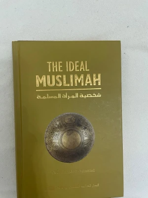 The Ideal Muslimah bok - 'The Ideal Muslimah' i guldtext. Boken är på engelska  och handlar om muslimska kvinnors personlighet och roll. Innehåller kapitel om äktenskap, familj och relationer.