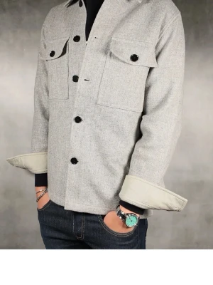 Ljusgrå overshirt med stora fickor - Stilren ljusgrå overshirt med svarta knappar och två stora bröstfickor med lock. Rak passform och uppvikta ärmar ger en avslappnad vibe. Perfekt att bära över en t-shirt eller hoodie. Materialet ser ut att vara mjukt och lite tjockare, troligen ullblandning.