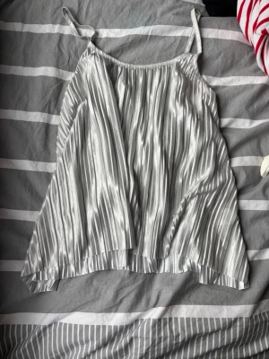 Silvrig festtopp - Snygg och enkel festtopp i silver🪩Perfekt för att pimpa upp en outfit inför en utgång eller ett finare tillfälle💕Flowig i passformen - den passar upp till M