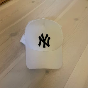 KEPS | NEW ERA. - Snygg vit keps från New Era med klassisk svart NY-logga framtill och mesh på sidorna för extra ventilation. Perfekt för dig som vill ha en stilren och sportig look. Snapback justering baktill.