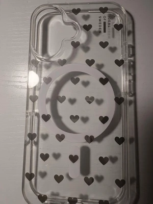 Transparent mobilskal med hjärtan - Snyggt transparent mobilskal från iDeal of Sweden med svarta hjärtan och MagSafe-kompatibilitet. Skalets kanter är genomskinliga och det har ett modernt, stilrent utseende som passar perfekt till din mobil. Tillverkat i tålig plast.