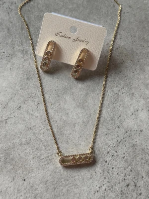 Guldpläterade örhängen med stenar - Snygga guldpläterade örhängen i rektangulär form med tre gnistrande stenar i varje. Örhängena har en modern design med små klara stenar längs kanterna för extra bling. Perfekt för dig som gillar trendiga accessoarer med lite extra detalj.