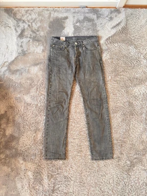 Han kjøbenhavn SS20 main - Säljer ett par grå slim fit jeans med klassisk femficksdesign och knappar . Jeansen har en smal passform och raka ben, perfekta till vardagslooken. 
