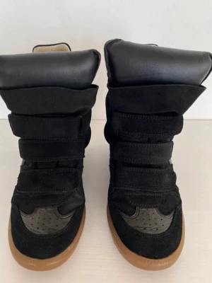 Isabel Marant skor - Säljer ett par svarta Isabel  Marant med högt skaft och flera breda kardborreband. Skorna har en kombination av mocka och textil samt detaljer i läderimitation. Sulan är i gummi med brun färg. Perfekta för dig som gillar en chunky och statement look.